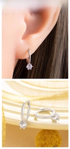 Close-up of silver-toned huggie hoop earrings featuring sparkling round-cut zircon stones