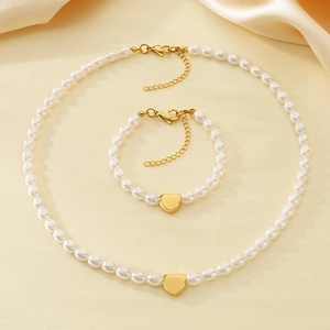Detail of elegant gold heart pendant pearl necklace and bracelet set on silk