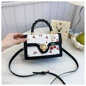 Detail of sweet cherry print bag showing woven handle and golden clover lock closure