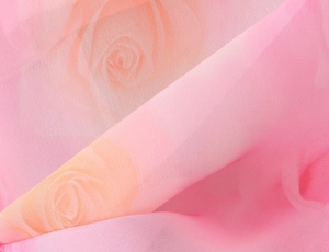 Detail of pink chiffon fabric with romantic rose prints and lightweight texture