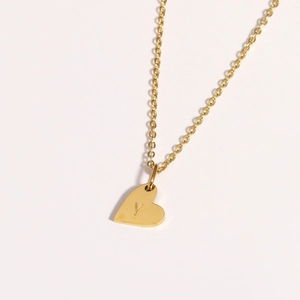 Gros plan du collier avec pendentif cœur doré gravé de la lettre Y sur fond neutre