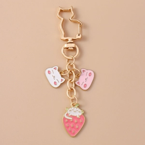 Detail view of cat charms on gold chain featuring white kitty and strawberry enamel pendants