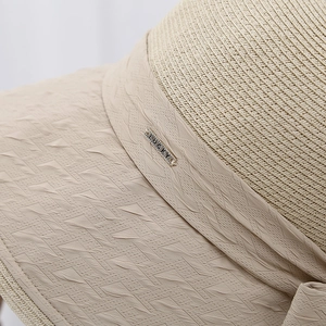 Detailed texture of straw beach hat with LUCKY metal badge and geometric fabric patterns