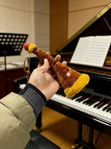 Detailed view of plush musical instrument keychain with woodwind design and bead strap