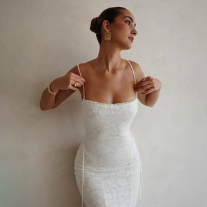 Détail de la robe moulante en dentelle blanche montrant la texture et les bretelles