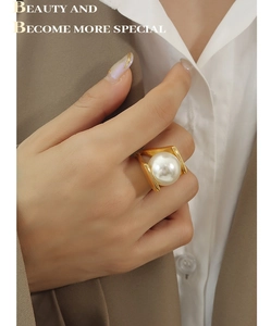 Close-up of a large white pearl ring in 18k gold finish worn by a model on hand