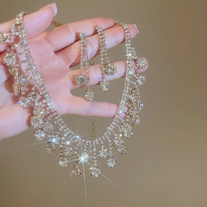 Close-up of sparkling zircon flower tassel necklace and earrings set held in hand