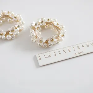Detail of woven faux pearl hair tie with small white flower and size scale ruler