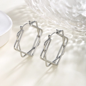 Close-up of interlocking rectangular silver hoop earrings with geometric 3D design