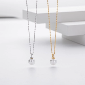 Detailed close-up of high-luster white pearl pendants on silver and gold chains