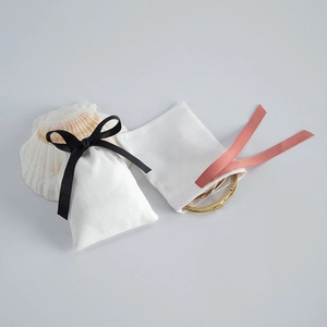 Elegant white velvet jewelry pouches with black bow drawstring and gold bracelet accessory