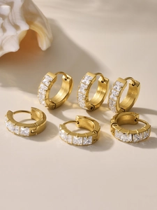 Close-up of three pairs of gold stainless steel hoop earrings with square cubic zirconia