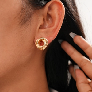 Close-up of golden layered geometric interlocking hoop earrings worn by a model