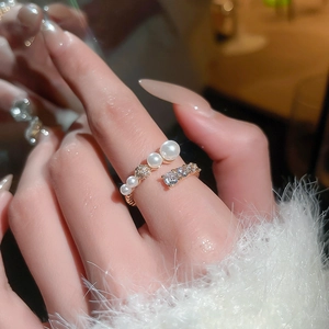 Detail of adjustable gold-plated ring with elegant pearls and sparkling zircon stones