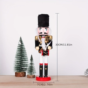 Detail of 30cm wooden nutcracker drummer with red uniform and festive Christmas trees