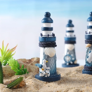 Mediterranean wood lighthouse ornament with seashells and fishnet on beach sand