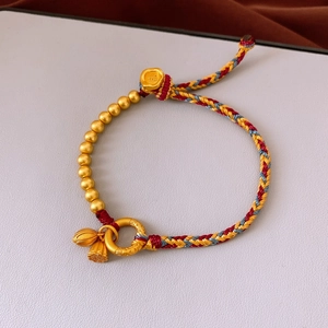 Macro view of woven cord bracelet featuring gold lotus charms and engraved beads