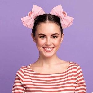 Close-up of pink satin bow hair claw clips on hair with vibrant purple background