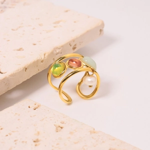 Detail of gold multi-layer ring with green and orange gemstones and a white pearl accent