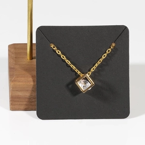 Minimalist gold necklace with geometric square pendant and clear zircon on a display card