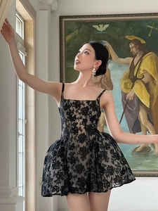 Détail de robe courte en dentelle noire avec motifs floraux et jupe évasée bouffante