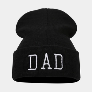Detailed view of white DAD embroidery on a black ribbed knit cuffed beanie hat