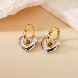 Detailed macro view of two-tone heart pendant earrings in gold and silver finish