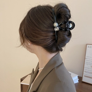 Detail of elegant black hair claw clip with grey pearl and crystal in a stylish hairstyle