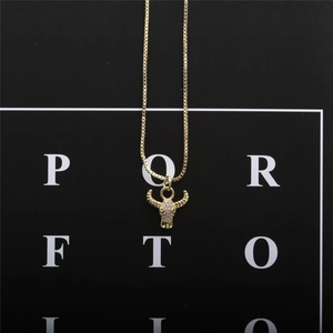 Detail of gold bull skull pendant with micro-set zircon stones on box chain