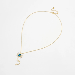 Macro shot of gold necklace featuring a blue rectangular stone and white zircons
