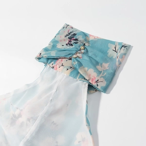 Dettaglio ravvicinato dell'abito a fiori blu con bottoni delicati e tessuto in chiffon