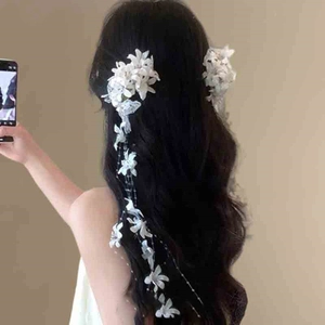 Detail of white floral hair clip featuring long lace tassels and faux pearl accents