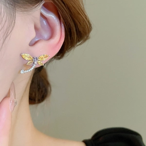 Close-up of model wearing a dragonfly stud earring with yellow and purple zircons