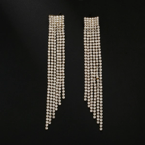 Macro detail of long tassel earrings with sparkling rhinestones on a sleek black background