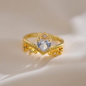 Macro detail of gold crown ring with a heart-shaped crystal on soft fabric