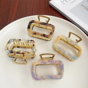 Detail of four acetate hair claws in tortoise shell and marble patterns on white plate