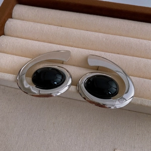 Detail view of silver spiral earrings with oval black gemstones in a velvet jewelry box