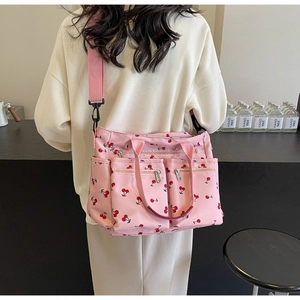 Pink tote bag with cherry print showing multiple zipper pockets on a nylon surface
