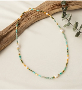 Detail of colorful beads and irregular pearls on a handmade necklace draped on wood