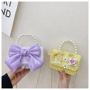 Detail of tweed kids handbags with pearl handles and bowknot in purple and yellow