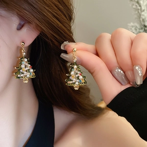 Close-up of festive Christmas tree drop earrings with green enamel and pearls