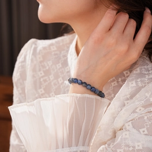 Close-up of blue kyanite beaded bracelet on a woman wrist with lace sleeve detail