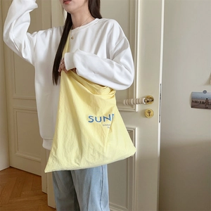 Detail of light yellow canvas tote bag with blue Sun Summer print on a casual model