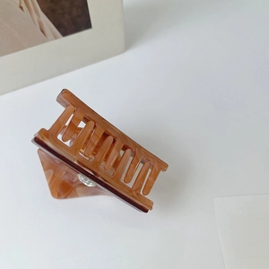 Detail showing tortoise shell acetate hair claw clip with a sparkling rhinestone accent