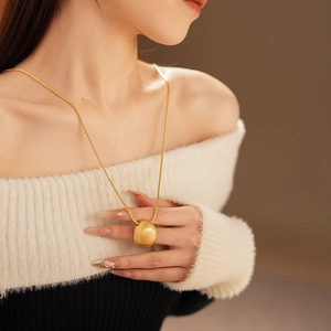 Détail d'une longue chaîne serpent dorée avec pendentif ovale sur un mannequin