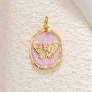 Macro detail of golden butterfly relief pendant with pink enamel and sparkling zircon