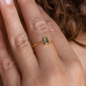 Detail shot of a rectangular green gemstone ring in a minimalist gold-tone setting