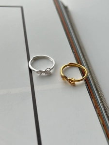 Detail of S925 stamp on silver and gold bow rings with shimmering zirconia accents