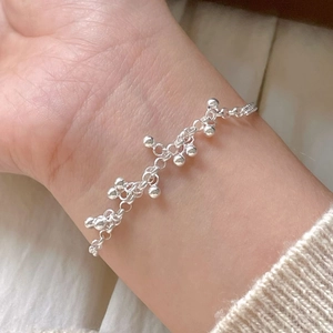 Minimalist 925 sterling silver beaded bracelet on a female wrist with beige knit sleeve