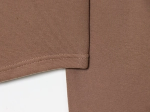 Macro shot of dark brown knit fabric showing precision double-stitch hem details